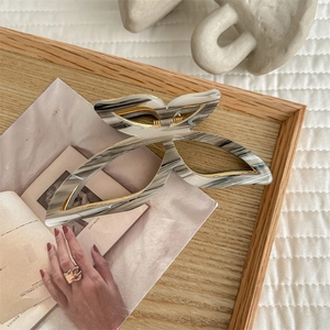 Detail of large butterfly claw clip with marble texture and gold metal frame on tray
