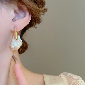 Primo piano di orecchini placcati oro 18K con perle barocche su orecchio donna