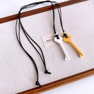 Detail of vintage key pendants in gold and silver finish on black leather cords