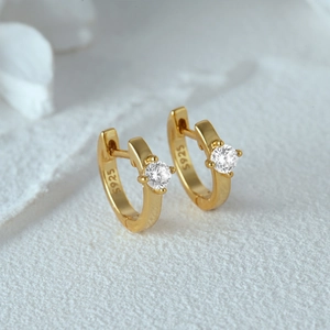 Detailed shot of gold-plated S925 sterling silver huggie earrings with round crystals