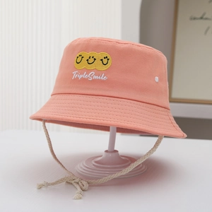 Close-up of pink canvas bucket hat with triple yellow smiles and adjustable chin strap