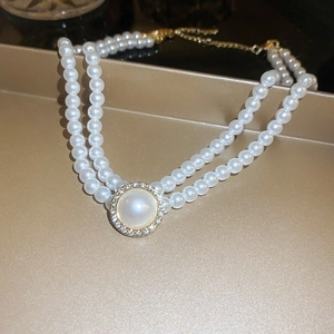 Détail d'un ras de cou en perles doubles avec pendentif en cristal sur plateau doré