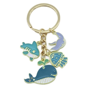 Golden enamel keychain with whale, shark, jellyfish, and ray ocean charms on white background