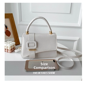 Miniature cream PU leather handbag with gold bar detail beside a phone for size comparison