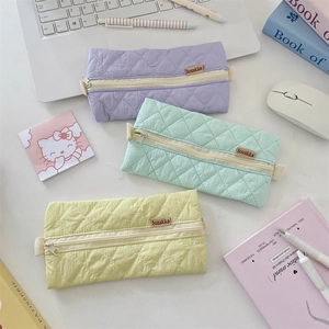Quilted macaron color pencil cases in purple green and yellow on a desk with stationery