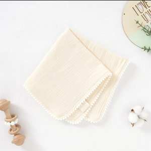 Débarbouillette en gaze de coton crème avec bordure pompons et décor hochet en bois