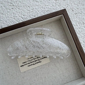 Detailed view of large transparent hair claw clip with white lace pattern texture