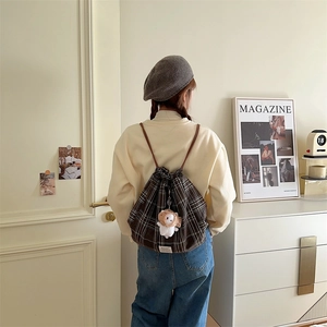Detailed view of brown plaid drawstring backpack with cute lion plush charm on a model