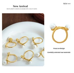 Close-up of a gold twist ring with two white pearls on a minimalist ceramic plate