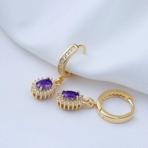 Macro shot of gold hoop earrings with oval purple stones and white zircon edging