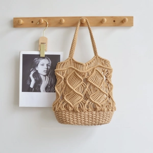 Minimalist khaki woven macrame tote bag with cotton string detail hanging on a wooden hook