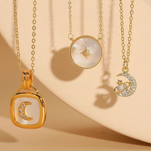 Detailed close-up of shell and zircon star and moon pendants on 14K gold plated chains