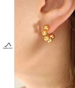 Detail of 18k gold plated stainless steel C-shaped earrings with bead texture
