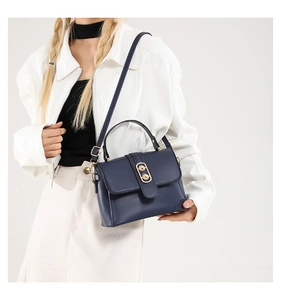 Deep blue leather handbag with golden double ring buckle shown on a model