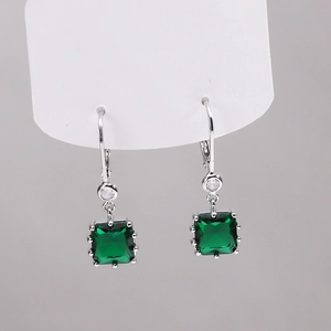 Vue détaillée de boucles d'oreilles dormeuses argentées avec zircons carrés vert émeraude