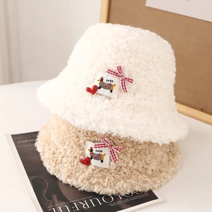 Détail d'un chapeau bob en laine d'agneau douce avec écusson chiot et nœud mignon