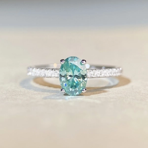 Macro shot of oval cut mint green moissanite stone in a 925 silver pave setting