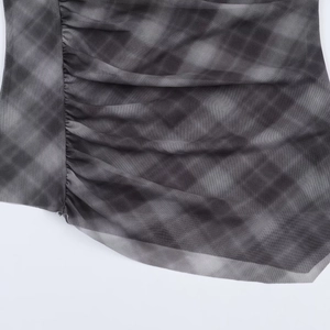 Close-up of mesh fabric texture and gray plaid print detailing on asymmetric skirt