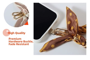Close-up of silk phone wrist strap featuring brown polka dots and gold metal hardware