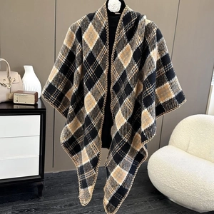 Detail of knit plaid shawl with V-neckline and decorative stitching on a black mannequin