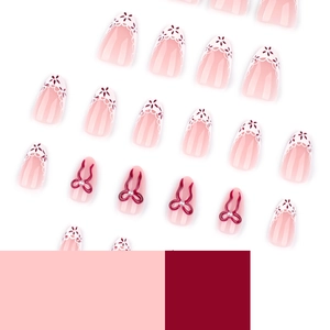 Pink almond press-on nails with 3D red ribbon bows, white lace patterns and pearl accents