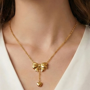 Chic gold stainless steel necklace with 3D bow and heart pendant on a model's neck
