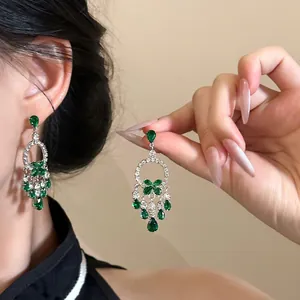 Close-up of emerald green tassel earrings featuring a silver base and sparkling gemstones