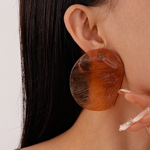 Macro view of oversized irregular amber resin stud earrings with brushed texture