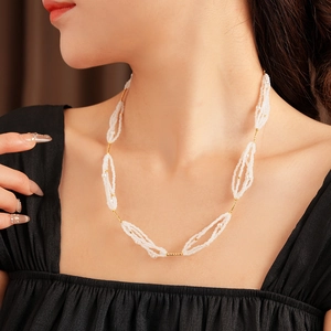 Detalle de collar de perlas con colgante circular dorado sobre un escote negro liso