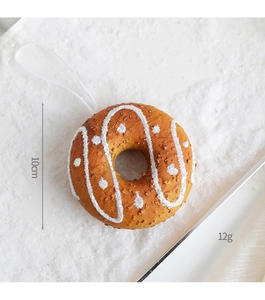 Detail of donut-shaped Christmas ornament with white icing texture on snow background