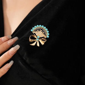 Close-up of vintage fan brooch with bow, turquoise beads and rhinestones on black velvet
