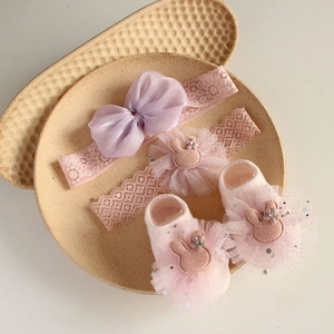 Detail view of pink and purple baby headband and socks set on a beige ceramic tray