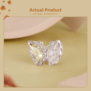 Detailed view of an S925 silver butterfly charm with yellow pear-shaped gemstone
