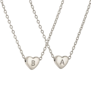 Close-up of heart-shaped stainless steel necklaces featuring engraved letters A and B