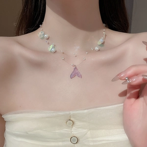Close-up of double-layer mermaid tail necklace with pearls and shell charm on collarbone