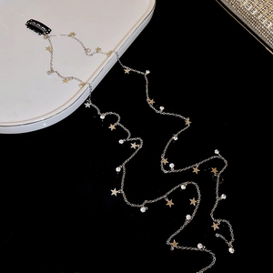 Détail de la longue chaîne à cheveux dorée avec étoiles scintillantes et pince noire