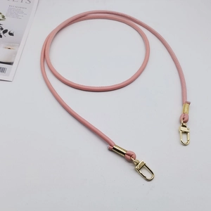 Dettaglio tracolla in pelle PU rosa con ganci a molla dorati e finiture metalliche