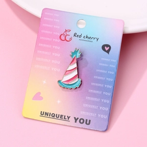 Detail of pink and white enamel party hat brooch pin displayed on branded paper card