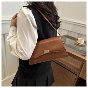 Brown leather vintage crossbody bag with golden buckle shown on a model's shoulder