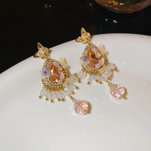 Macro detail of vintage tassel earrings with champagne crystal and butterfly studs