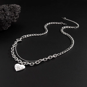 Double-layered silver necklace featuring a flame heart pendant on dark rock base