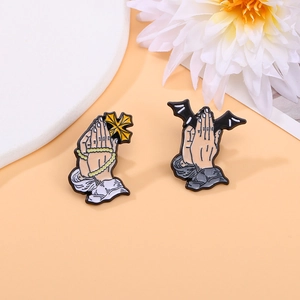 Cartoon enamel brooch set with praying hands holding a gold cross and black bat