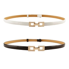 Detail of adjustable pearl buckle skinny belts in black and white with clover metal clasp
