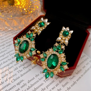 Macro shot of emerald green oval earrings with diamond halo on a vintage book