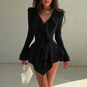 Détail de la robe noire à col en V profond avec taille à basque et poignets évasés
