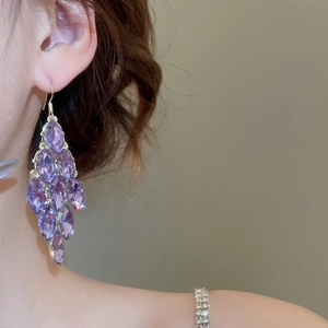 Detail of gold earrings with cascading purple marquise-cut crystals and fringe tassel