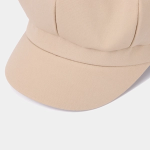 Detailed close-up of stitching and twill texture on a beige cotton newsboy cap