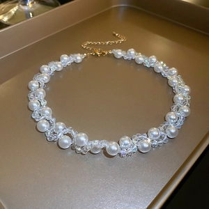 Close-up of French vintage faux pearl and crystal choker necklace on a matte gold tray