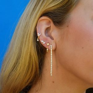 Close-up of gold butterfly and leaf stud earrings with white zircon on model's ear