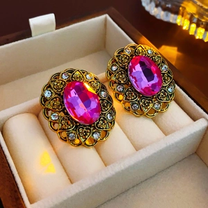 Close-up of vintage gold oval earrings with pink gems and diamonds in a velvet box